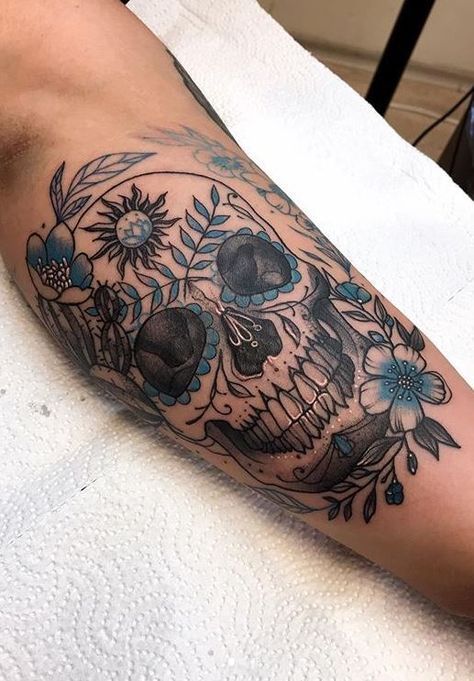 Blue botanical sugar skull forearm tattoo with flowers and leaves