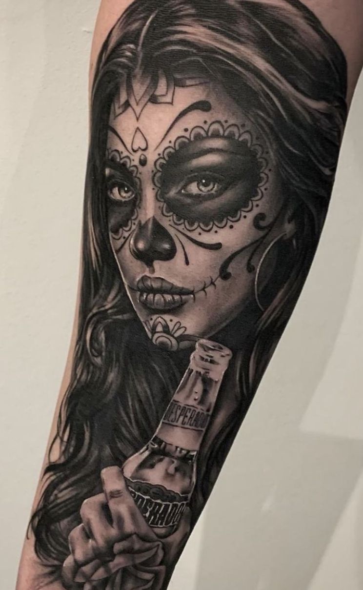 Black and grey Catrina portrait tattoo holding a bottle on the forearm